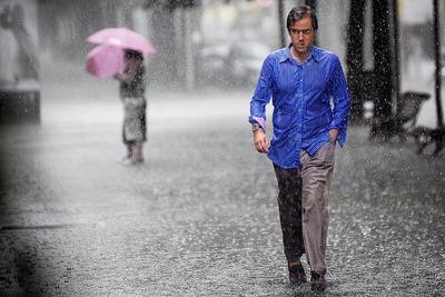 Человек идет под дождем с зонтом под дождем. | Премиум Фото