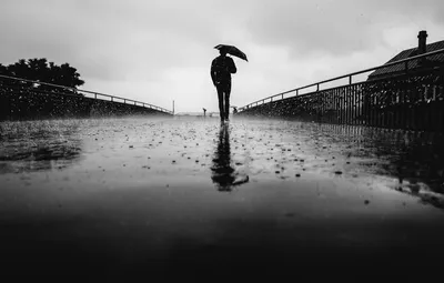 Человек идет под дождем с зонтом. | Премиум Фото